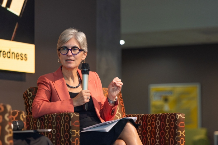 Woman seated while speaking into a microphone.