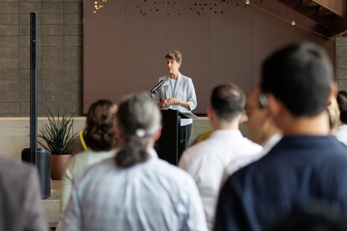 Woman speaking at a lectern to an audience.